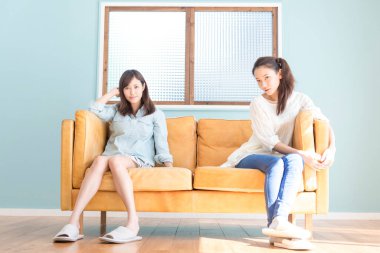 Evdeki kanepede oturan Asyalı kadınlar. 