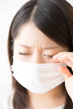 Soluk maskeli hasta bir Asyalı kadının portresi beyaza izole edilmiş.