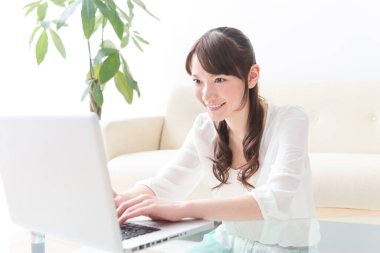 Evde dizüstü bilgisayar kullanan Asyalı genç bir kadın. 