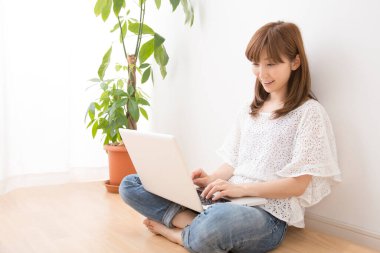 Evde dizüstü bilgisayarı olan gülümseyen güzel bir Japon kadın.