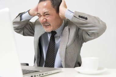 Beyaz arka planda dizüstü bilgisayarla çalışan olgun Asyalı iş adamının portresi