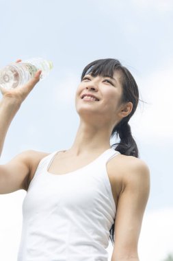 Yaz parkında koşu yaparken su içen güzel Japon kadın. 