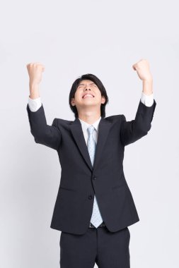 Resmi takım elbiseli Asyalı genç işadamı zaferi kutluyor.