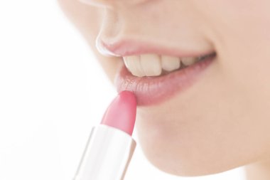 Genç Asyalı bir kadın kırmızı ruj sürüyor, stüdyo fotoğrafı. 