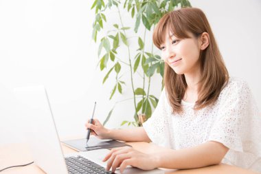 Dizüstü bilgisayar ve grafik tableti ile çalışan kadın grafik tasarımcısı