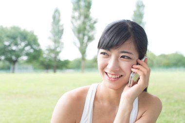 Parkta cep telefonu kullanan genç bir kadın. 