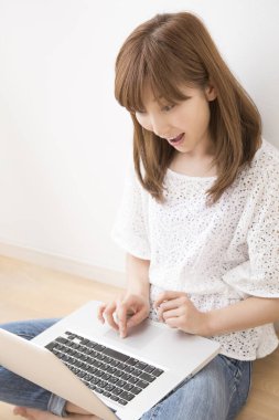 Evde dizüstü bilgisayarı olan gülümseyen güzel bir Japon kadın.