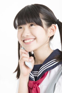 Okul üniformalı, beyaz arka planda cep telefonu olan güzel bir öğrencinin portresi.