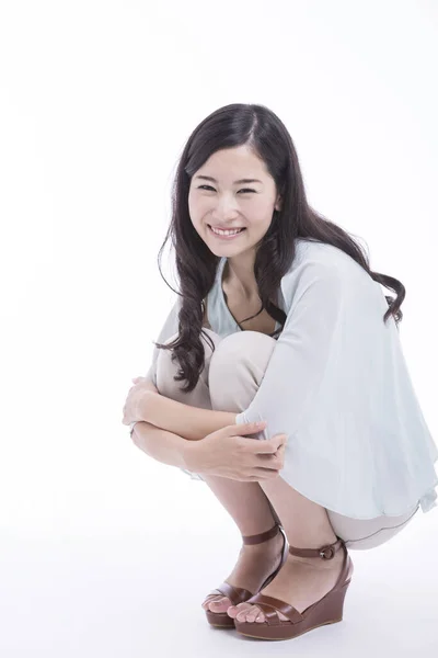 スタジオの床に座っている若いアジア人女性の肖像画は 白い背景の上に隔離されています — ストック写真