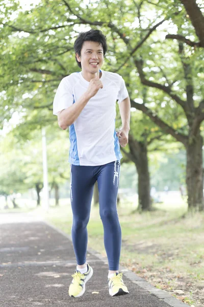 Sportif Japon adam yaz parkında koşuyor. 