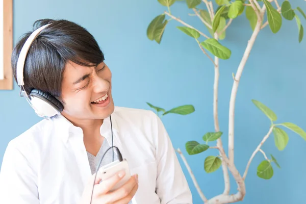 亚洲年轻男子戴着耳机听音乐 — 图库照片