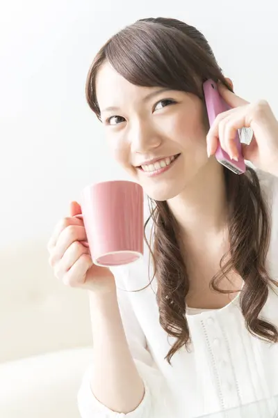 woman drinking a cup of coffee  and talking on  smartphone