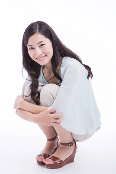 一个年轻的亚洲女人坐在工作室的地板上 被白色背景隔离的肖像 — 图库照片