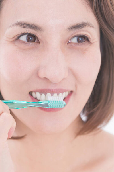 beautiful Japanese woman brushing her teeth on white background