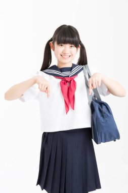 Okul üniformalı güzel bir öğrencinin portresi beyaz arkaplanı işaret ediyor.