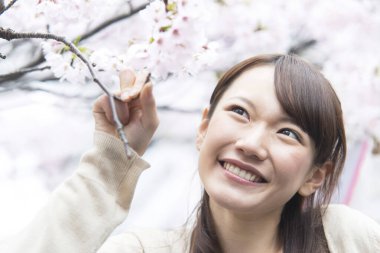 Parkta çiçeklerle gülümseyen kadın. 