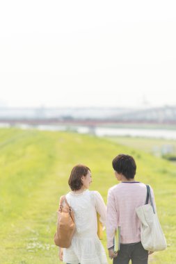 Bir çift mutlu genç Japon öğrenci doğada birlikte vakit geçiriyorlar.