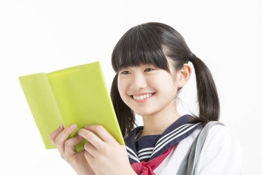 Okul üniformalı, beyaz arkaplan üzerine kitabı olan güzel bir öğrencinin portresi.