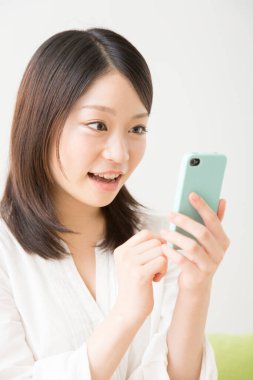 Beyaz üzerine izole edilmiş akıllı telefon kullanan güzel Asyalı bir kadının portresi.