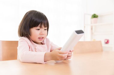 Küçük Asyalı kız uzaktan kumanda kullanıyor.