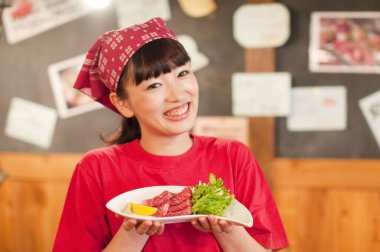 Gülümseyen kadın elinde taze yiyecek tabağı tutuyor.