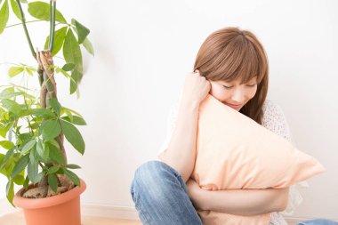 Üzgün kadın yastıkla yerde oturuyor. 