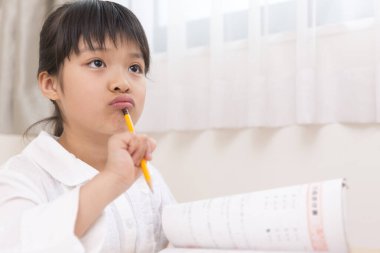 Küçük Asyalı kız ödevini yapıyor. 