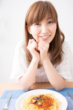 Masasında makarna olan güzel bir genç kadının portresi. 