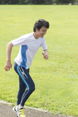 Sportif Japon adam yaz parkında koşuyor. 