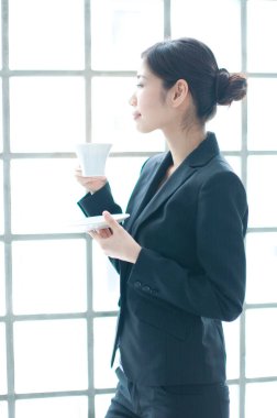 Genç iş kadını kahve içiyor ve düşünüyor.