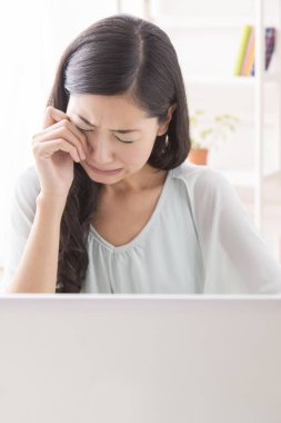 Bilgisayar kullanan üzgün Asyalı genç kadın. 