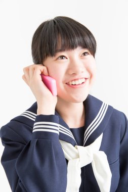 Okul üniformalı genç Asyalı kızın portresi akıllı telefondan konuşuyor.