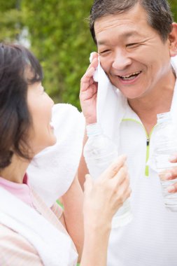 asian senior couple  drinking water in park after training 