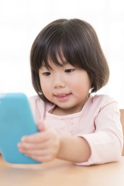 Küçük sevimli Asyalı kız telefon kullanıyor.