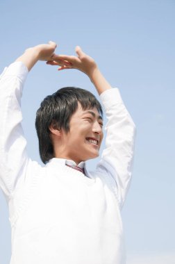 Ellerini gökyüzüne kaldırmış genç bir adam. 