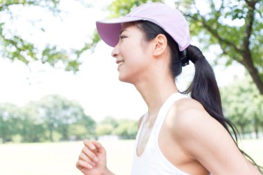 Spor yapan Japon kadın yaz parkında koşuyor. 