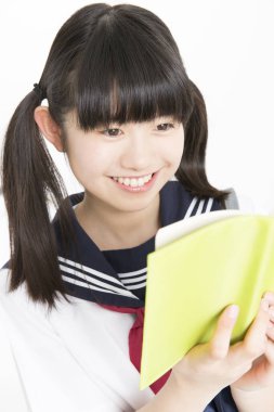 Okul üniformalı, beyaz arkaplan üzerine kitabı olan güzel bir öğrencinin portresi.