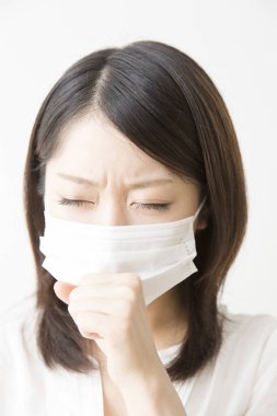 Soluk maskeli hasta bir Asyalı kadının portresi beyaza izole edilmiş.