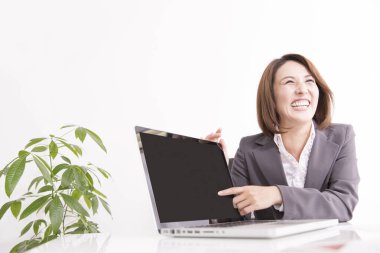 Ofiste dizüstü bilgisayarı işaret eden olgun Japon iş kadını portresi.