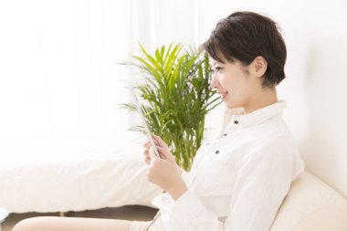 Evde dijital tabletli Asyalı kadın 