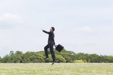 Orta sahada çantalı genç iş adamı 