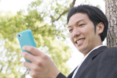 Parkta cep telefonu kullanan mutlu iş adamı 