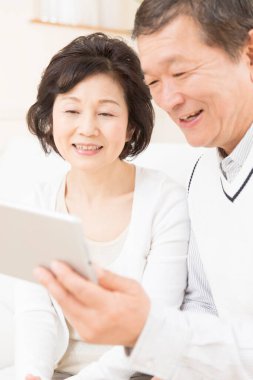 Evde dijital tablet kullanan Asyalı yaşlı çift