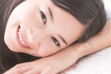 Kanepede uzanmış kameraya bakan Asyalı kadın.