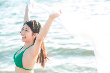 Deniz kenarında poz veren mutlu Asyalı kadın.