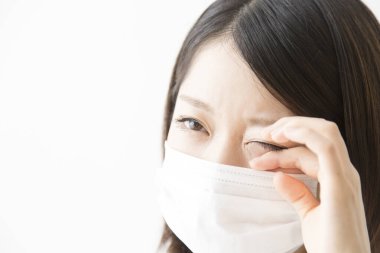 Soluk maskeli hasta bir Asyalı kadının portresi beyaza izole edilmiş.