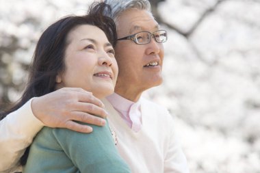 Güzel Asyalı olgun çifti ağaçlarla parka kapatın.