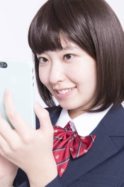 Akıllı telefon kullanan gülümseyen Japon öğrencinin stüdyo portresi