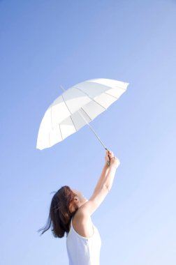 Güzel Asyalı kadın deniz kenarında şemsiyeyle poz veriyor.