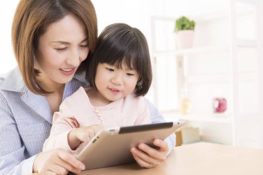 Tablet kullanan Asyalı bir kadın ve bir çocuk.